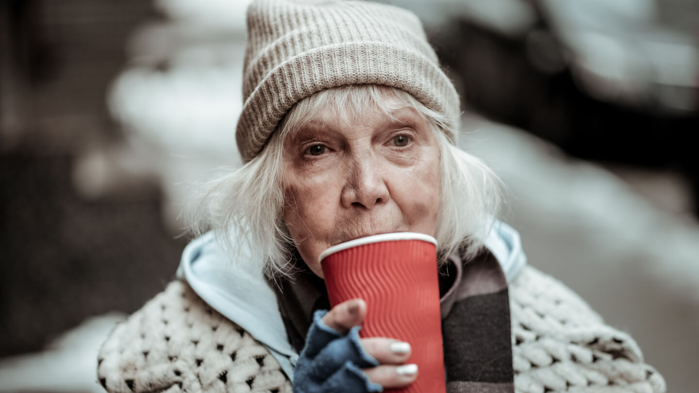 homeless woman sipping from a cup.